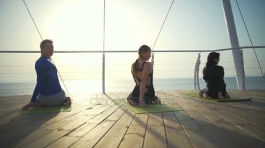 Üç kişi egzersizleri yapıyor halı üzerinde oturan bech ağır çekim yakın: