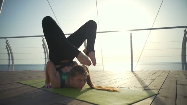 Молодая женщина делает жесткие упражнения на зеленом ковре рядом с пляжем — стоковое видео