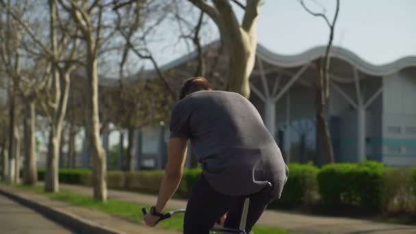 Young man in grey shirt riding a bike on the street slow motion — Stock Video