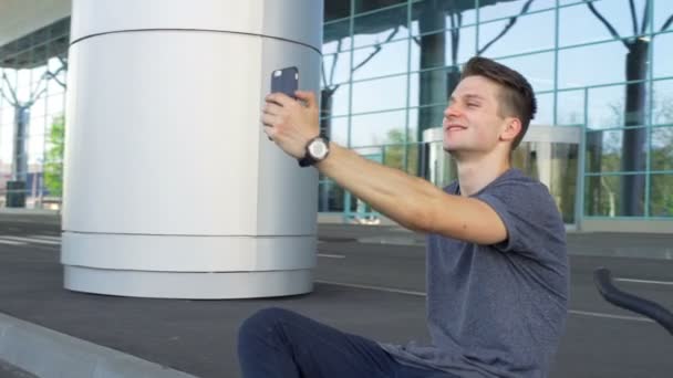 Ung man sitter på gränsen och att göra en selfie slowmotion — Stockvideo