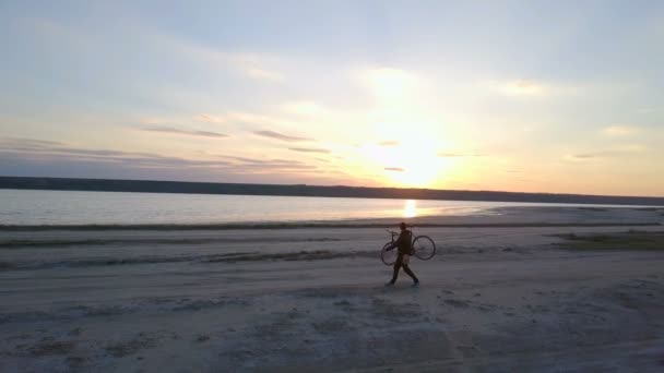 El hombre lleva su bicicleta y mira el atardecer en las imágenes del dron kuyalnik — Vídeos de Stock