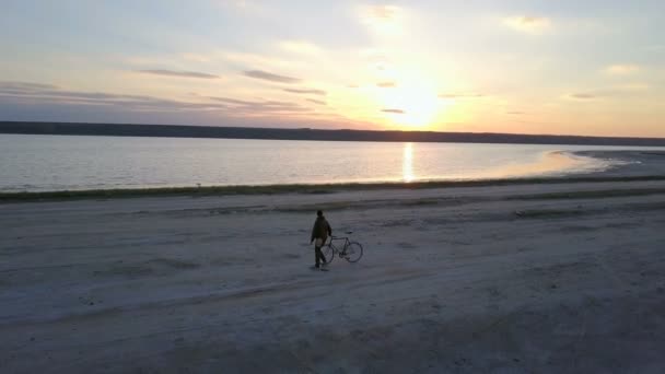 Homem sentado em sua bicicleta e olhando para o pôr do sol no kuyalnik na Ucrânia — Vídeo de Stock