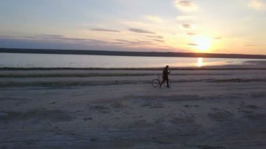 Bisiklet ile yürüyüş ve telefona kuyalnik dron görüntüleri yakın tutan bir adam