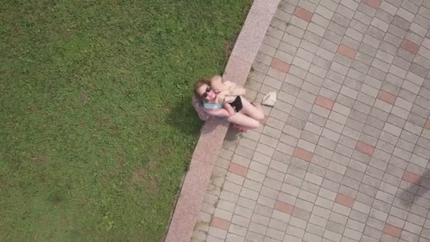 Drone filmagem de uma jovem mãe com seu bebê playfull sentado na fronteira — Vídeo de Stock