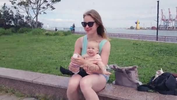 Όμορφη νεαρή μητέρα κάθεται στα σύνορα με το μωρό — Αρχείο Βίντεο
