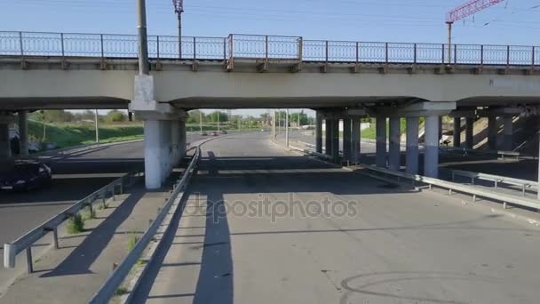 Antenn drönare bilder av en man som rider sin cykel under en järnvägsbro — Stockvideo