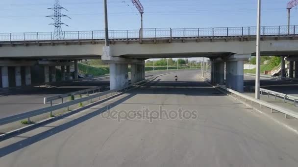 Mann fährt mit Fahrrad unter Brücke in Zeitlupe auf Drohne zu — Stockvideo