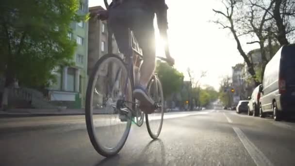 Hombre tatuado en camisa a cuadros montando su bicicleta en la ciudad cámara lenta — Vídeo de stock