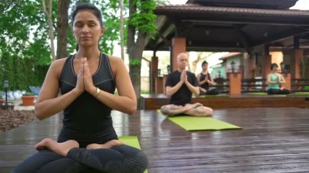 Grupo de pessoas meditando sobre o parquete de madeira câmera lenta — Vídeo de Stock