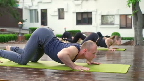Group of people standing in the downward-facing dog position slow motion — Stock Video