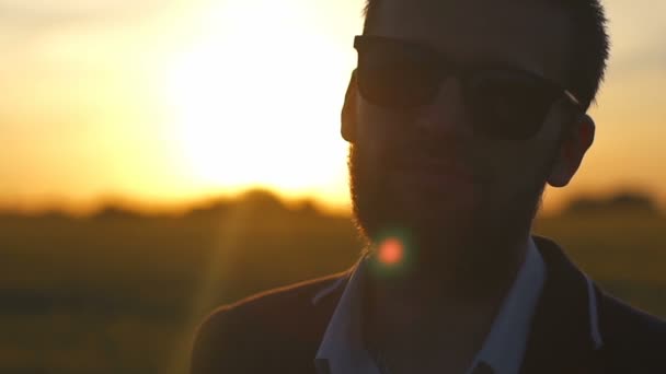 Portrait d'un bel homme portant des lunettes au coucher du soleil dans un champ au ralenti — Video