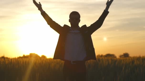 Silhouette man in a suit pray in the sunset field glare slow motion — Stock Video