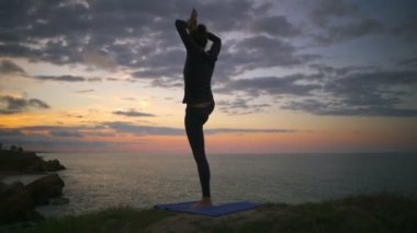 Huzurlu kız Yoga poz gündoğumu cliff ağır çekim sırasında yapıyor