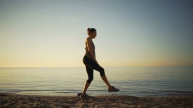 Germe fitness kadın hamle streç egzersiz okyanus gündoğumu ağır çekim yapıyor