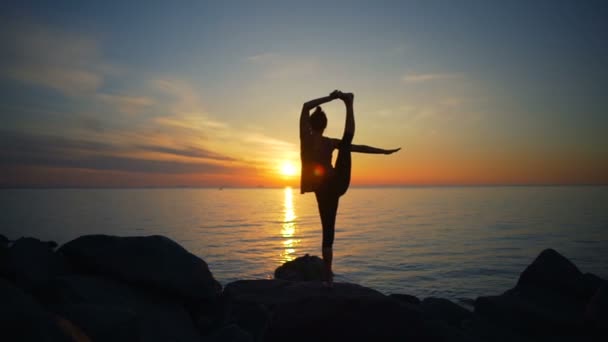 Gesunde junge Frau praktiziert Yoga auf der Klippe Meerblick Morgendämmerung Zeitlupe — Stockvideo