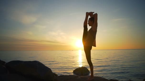 Saudável jovem mulher flexível fazendo ioga asanas costa do mar nascer do sol câmera lenta — Vídeo de Stock