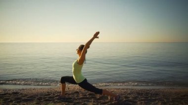 Esnek sağlıklı genç kızı pratik yoga beach sealine gündoğumu ağır çekim