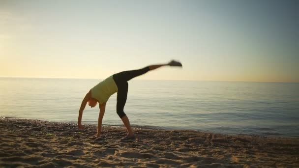 Flexibele gelukkig jong meisje turn kar-wielen sealine zonsopgang Slowmotion — Stockvideo