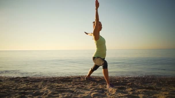 Ευέλικτη υγιή νεαρά γυναίκα πρακτική γιόγκα παραλία sealine sunrise αργή κίνηση — Αρχείο Βίντεο