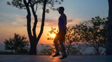 Siluet adam ip egzersiz açık gün batımından yavaş atlama ile atlama