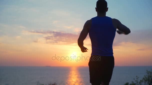 Young strong healthy man run raising arm celebrating win dawn sea slow motion — Stock Video