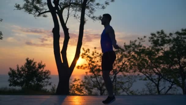 Silueta fuerte Hombre bien construido Saltar la cuerda entrenamiento al aire libre puesta del sol slow motion — Vídeos de Stock