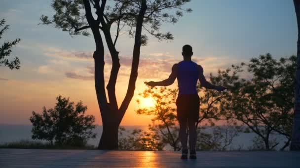 Güçlü adam exersice atlama ipi egzersiz açık gün batımından slowmotion siluet — Stok video