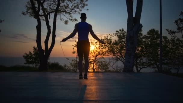 Siluet güçlü sağlıklı adam atlama ipi egzersiz açık şafak slowmotion — Stok video