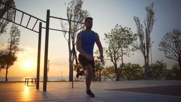 Homem forte saudável envolvido em exercícios trx salto treino ao ar livre alvorecer lentidão — Vídeo de Stock