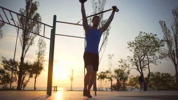 Hombre fuerte comprometido en trx ejercicio embestida hacia adelante entrenamiento al aire libre amanecer slow motion — Vídeos de Stock