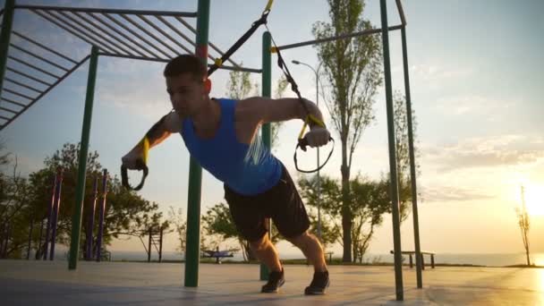 Homem forte quente envolvido em exercícios trx puxar para cima treino ao ar livre alvorecer lentidão — Vídeo de Stock