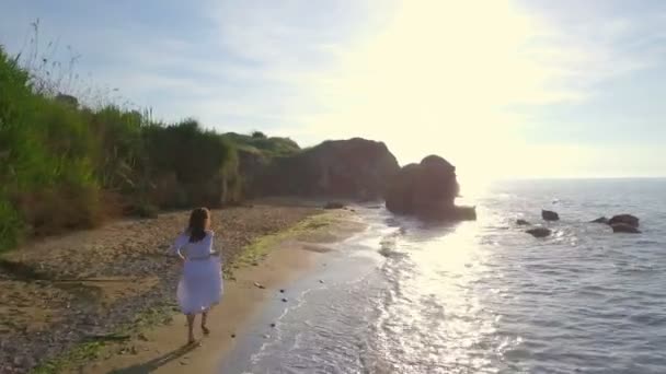 Жіноча красива романтична щаслива жінка біжить на пляжі хвиля морський схід безпілотник кадри — стокове відео