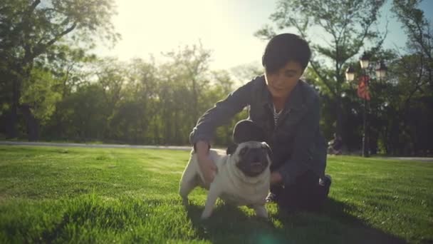 Joven hermosa chica jugar corteza pequeño cachorro pug crianza parque verano sol cámara lenta — Vídeo de stock