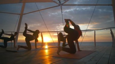 Siluet grup kadınlar yoga asanas yoga sınıf deniz şafak ağır çekim pratik