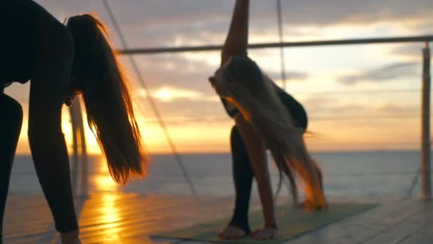 Grupo silhueta mulheres trikonasana asanas ioga classe praia mar amanhecer câmera lenta — Vídeo de Stock