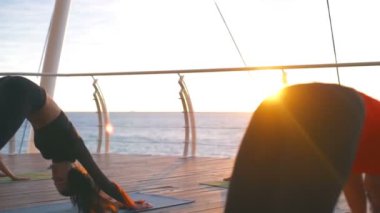 Yoga sınıf genç kadın grup uygulama asana aşağı köpek günbatımı deniz ağır çekim