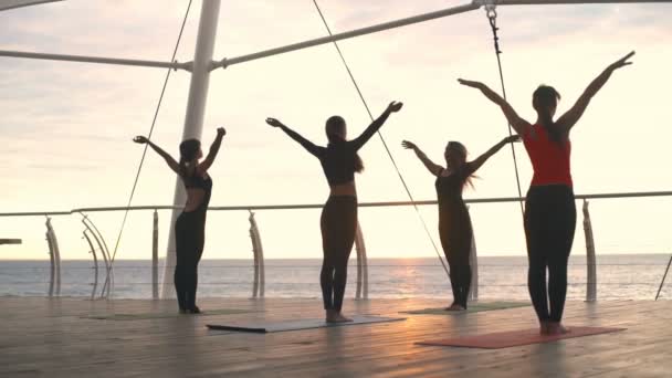 Yoga klass ung kvinna gruppövning yoga asana namaste sunset sea slowmotion — Stockvideo