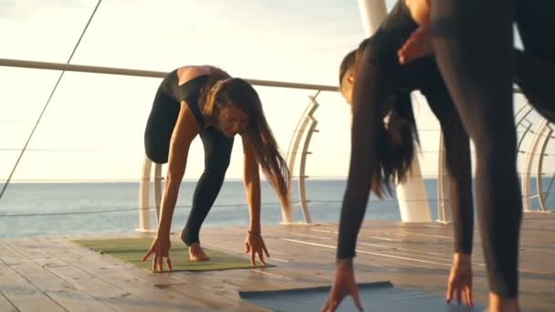 Yoga classe grupo menina prática ioga Pose na ponta do pé pôr do sol mar câmera lenta — Vídeo de Stock