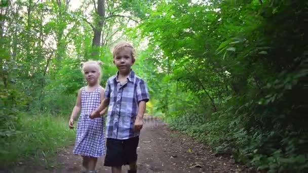 Kleine koppel jongen meisje bedrijf handen lopen glimlachend zonnige park snelle Slowmotion — Stockvideo