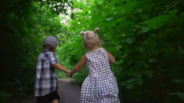 Pareja pequeña chico chica cogido de la mano corriendo soleado parque árboles rápido cámara lenta — Vídeo de stock