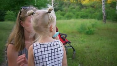 Wipe gözyaşları kızı güneşli park hızlı ağır çekim tutun anne iki bebek kız ağlıyor