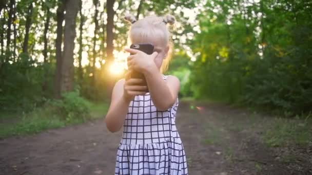 Vacker blond tjej använda telefonen gör foton selfie solig park snabba slowmotion — Stockvideo