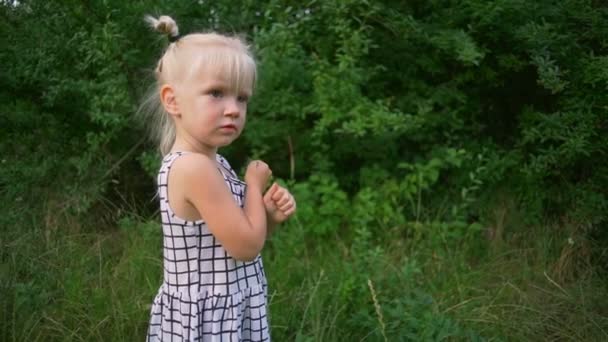 Petite belle blonde séjour dans l'herbe verte parc ensoleillé au ralenti rapide 