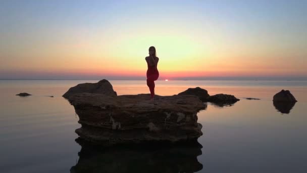 年轻女孩做瑜伽 garudasana 鹰姿势海礁黎明无人机画面空中 — 图库视频影像