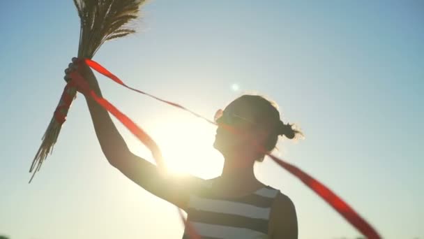 Chica joven vestido a rayas con racimo de trigo rojo cinta campo sol rápido cámara lenta — Vídeos de Stock
