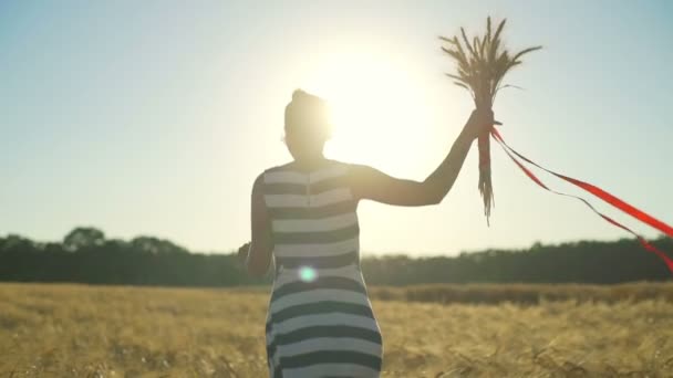 Chica joven ejecutar ramo de campo trigo cinta roja aleteos sol rápido cámara lenta — Vídeo de stock