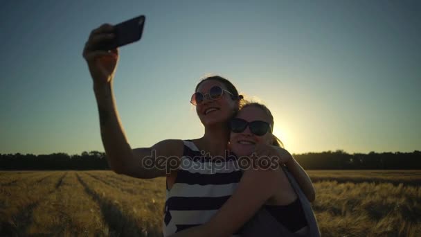 Twee Smiling vriendinnen in sunglass maken selfie in veld zonnige snelle slow-motion. — Stockvideo