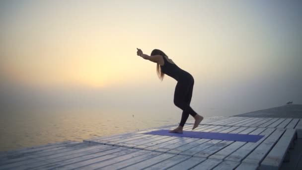 Genç kadın ince siyah giymek yapmak yoga denge poz gündoğumu sis hızlı yavaş hareket — Stok video