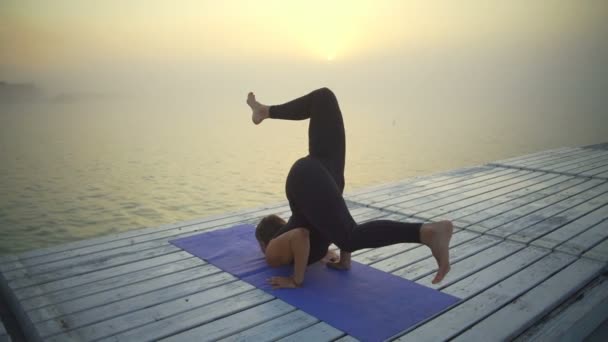 Молодая девушка стройная черная одежда сделать стойку на голове йоги позе восхода солнца туман быстрое замедленное движение — стоковое видео