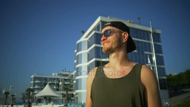 Красивий усміхнений чоловік сонцезахисні окуляри борода залишатися на узбережжі сонячно швидкий повільний рух — стокове відео